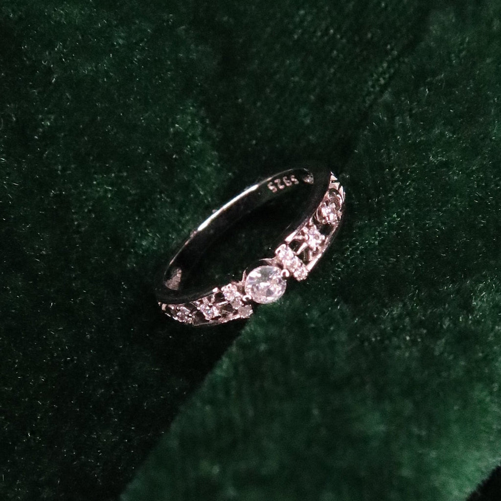 Sterling silver band with a round center stone and intricate side detailing, displayed on deep green velvet fabric for an elegant, refined presentation.