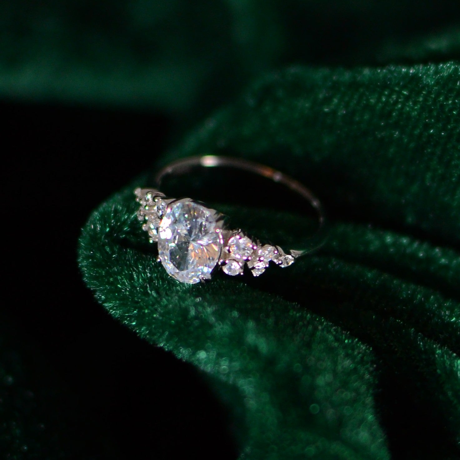 Elegant sterling silver ring featuring an oval-cut center stone and tapered side stones, showcased on deep green velvet for a luxurious, timeless look.