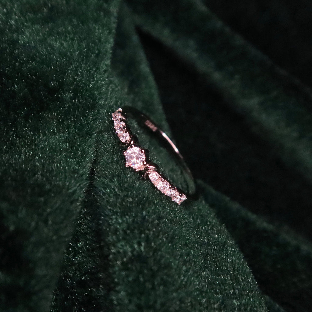 Delicate ring with small diamonds on a dark green fabric background