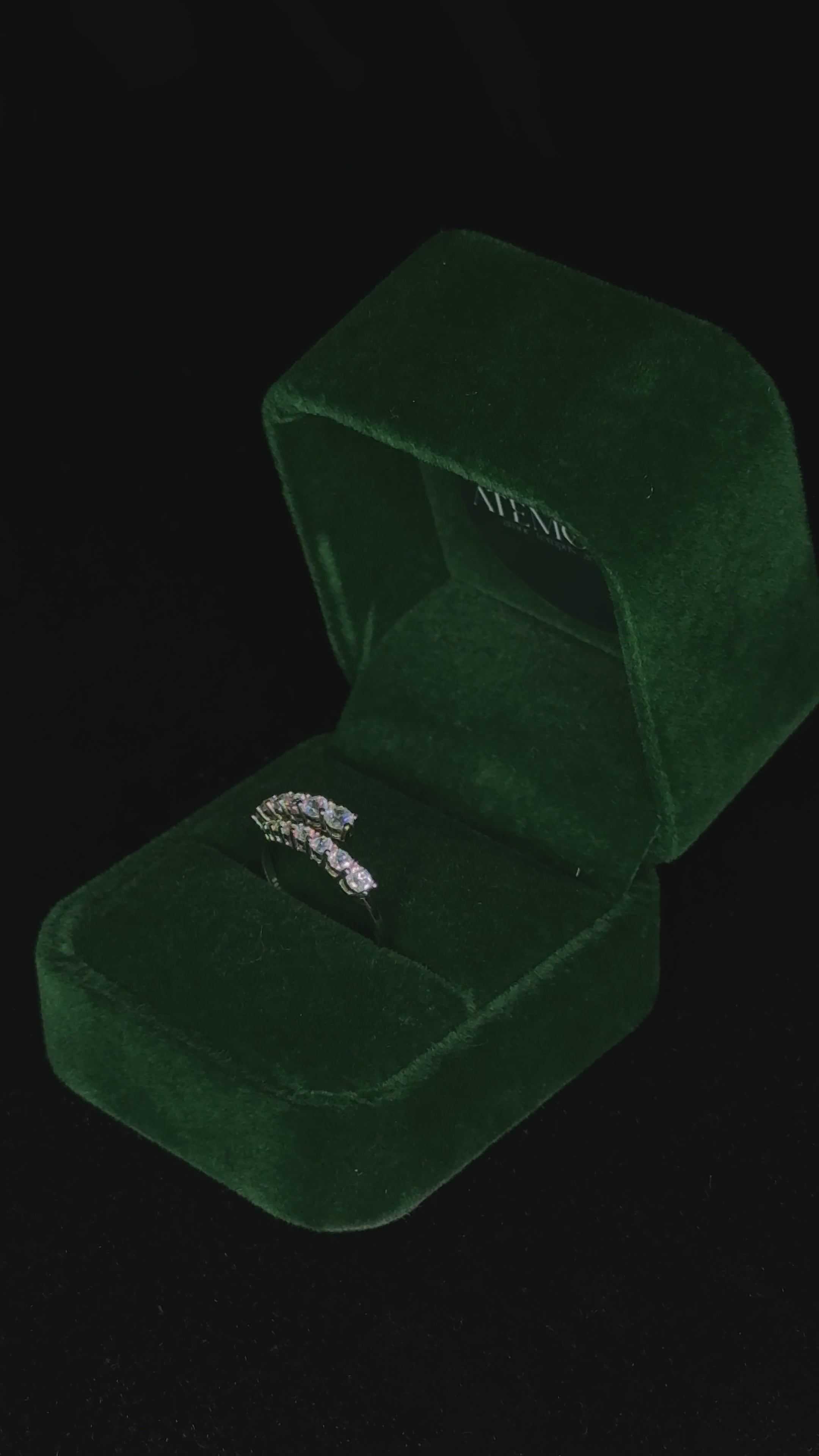 Video of a sterling silver ring with graduated round stones rotating inside a green velvet jewelry box, catching the light to highlight its sparkle and fine craftsmanship.